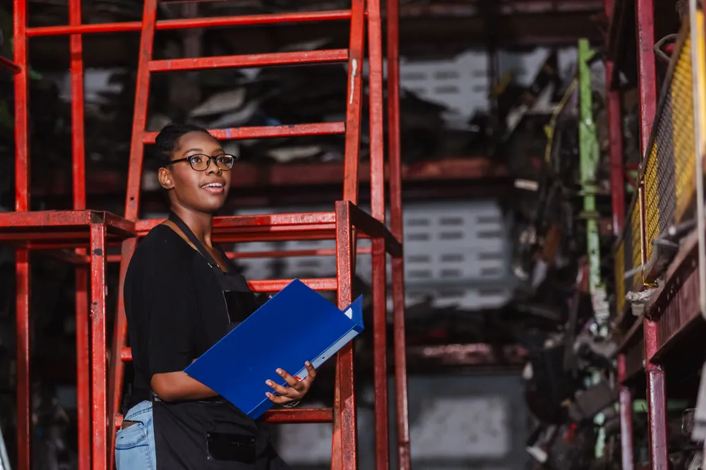 Female safety officer with clipboard conducting an audit at an auto parts factory